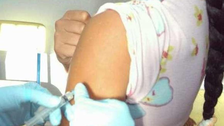 Un sanitario vacuna a una niña contra la gripe.