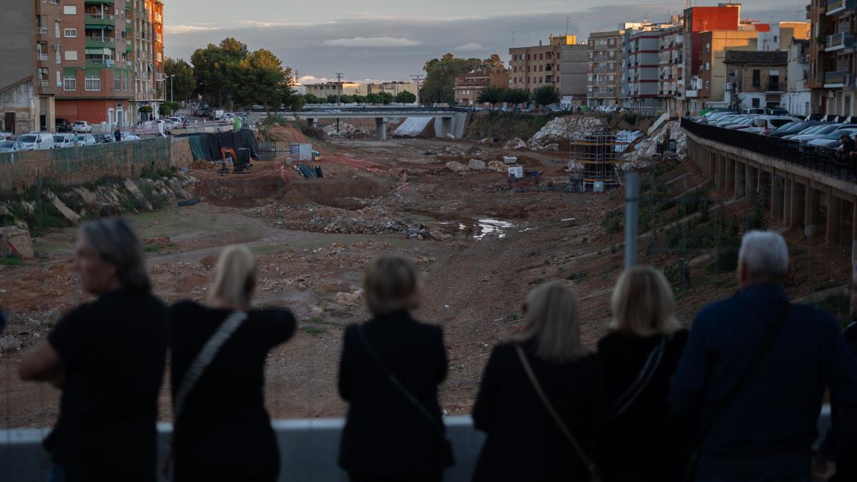 Varias personas hacen una cadena humana para homenajear a las víctimas de la dana, en la Rambla del Poyo, a 26 de octubre de 2025, en Paiporta