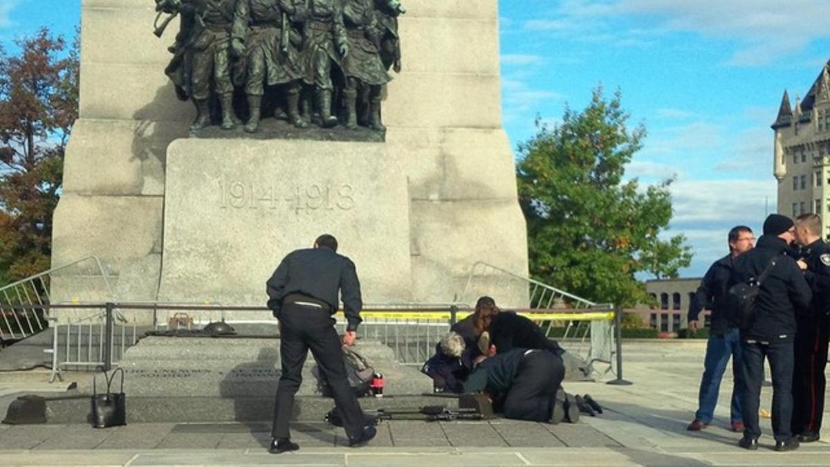 Unos soldados atienden a un compañero herido, ayer ante el monumento de los veteranos de guerra en Ottawa.