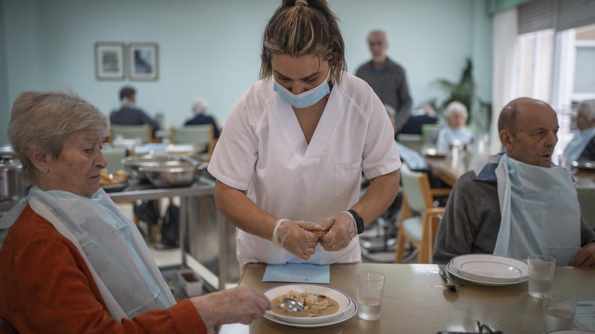 Una trabajadora ayuda a una usuaria con la comida.