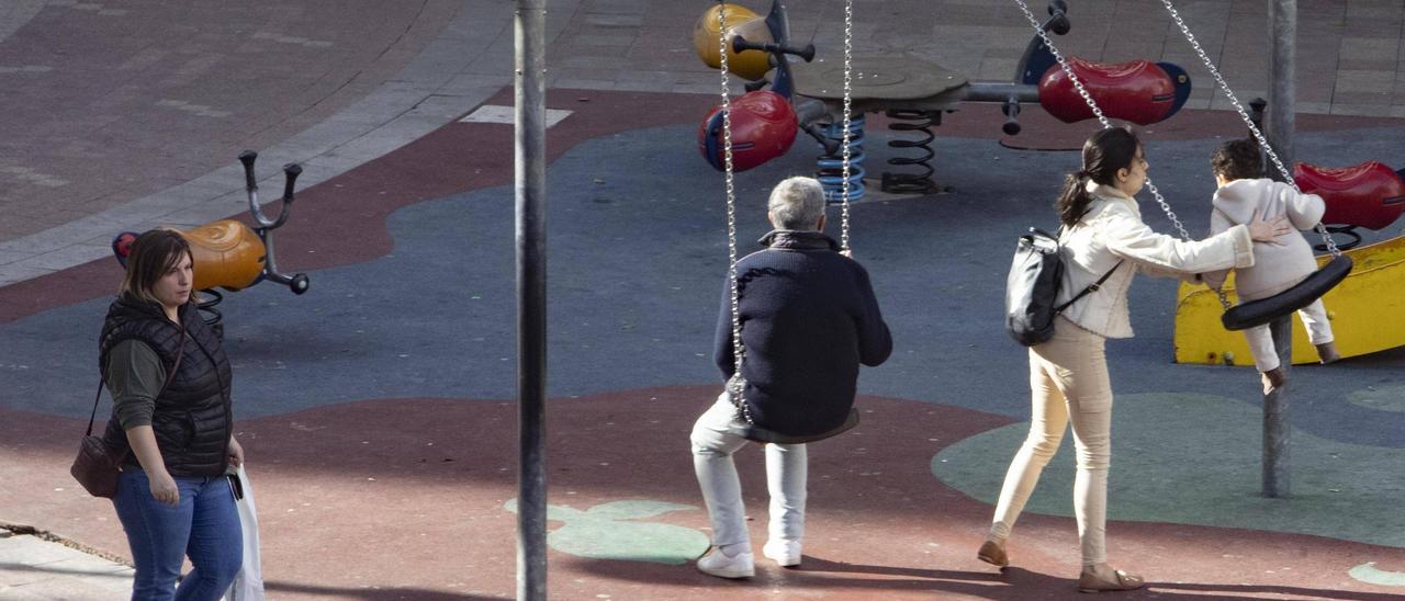 Una niña se columpia en los juegos infantiles de la plaza Mayor de Alzira.