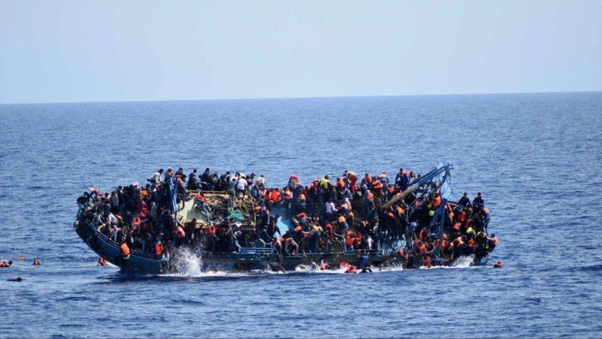 Migrantes se agolpan en una barcaza en el mar.