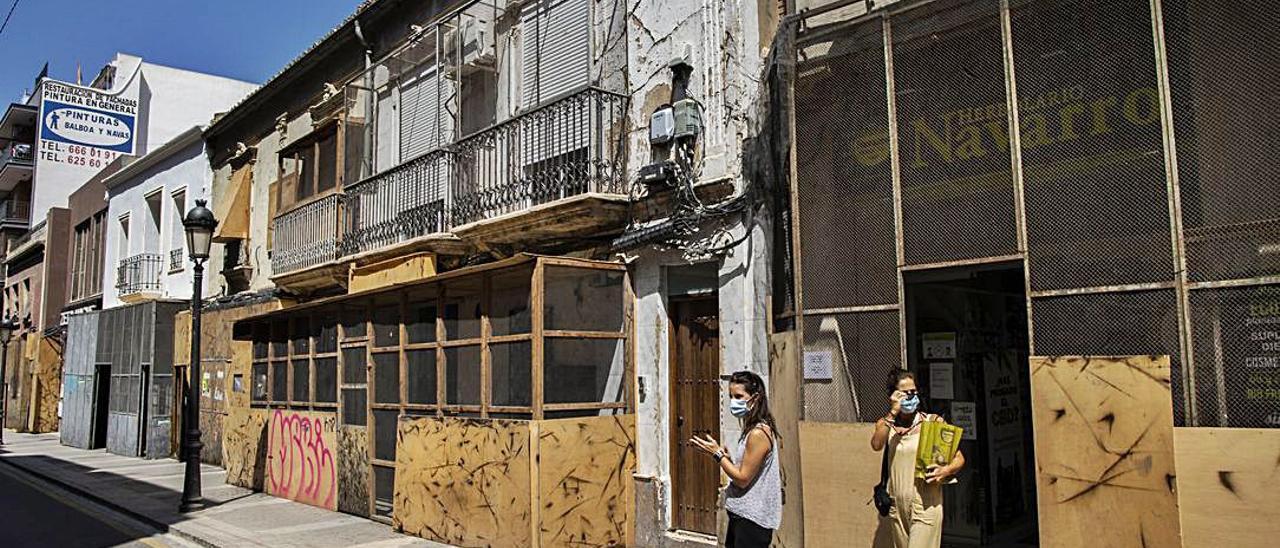 Una familia camina por la calle Mayor de Paterna, junto a edificios enfundados de protecciones. | GERMÁN CABALLERO