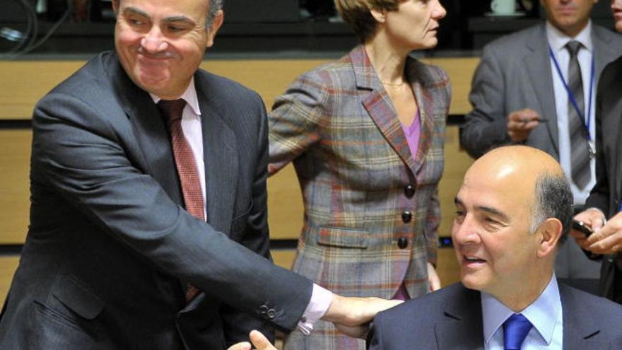 El ministro español de Economía, Luis de Guindos, saluda al ministro francés de finanzas, Pierre Moscovici.