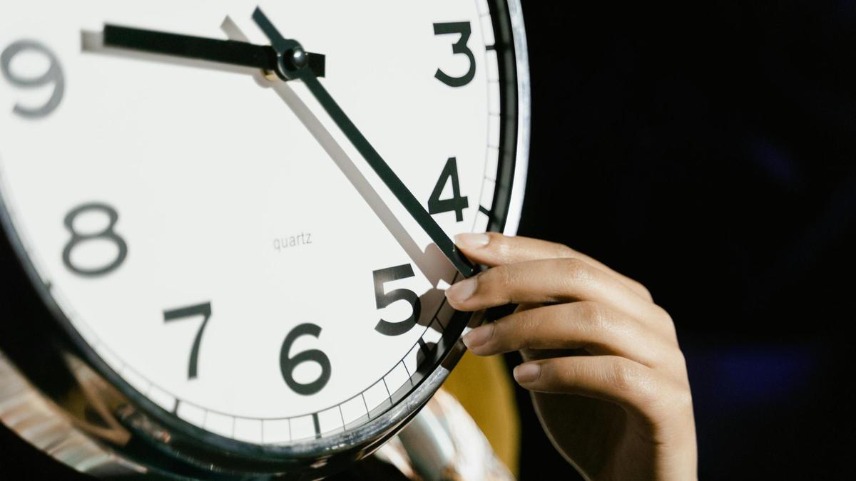 Imagen de una mujer cambiando la hora en el reloj