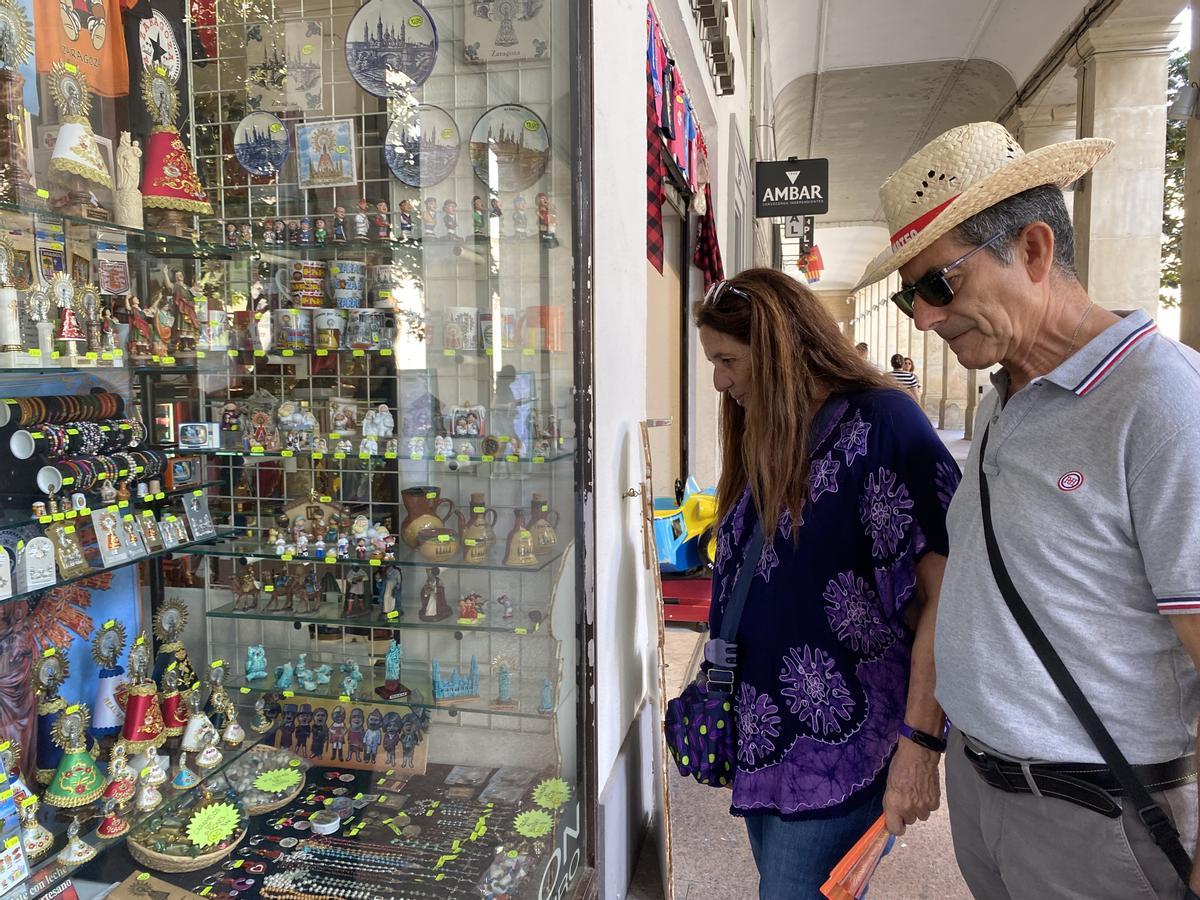 Dos turistas ojeando el escaparate de una tienda de recuerdos.