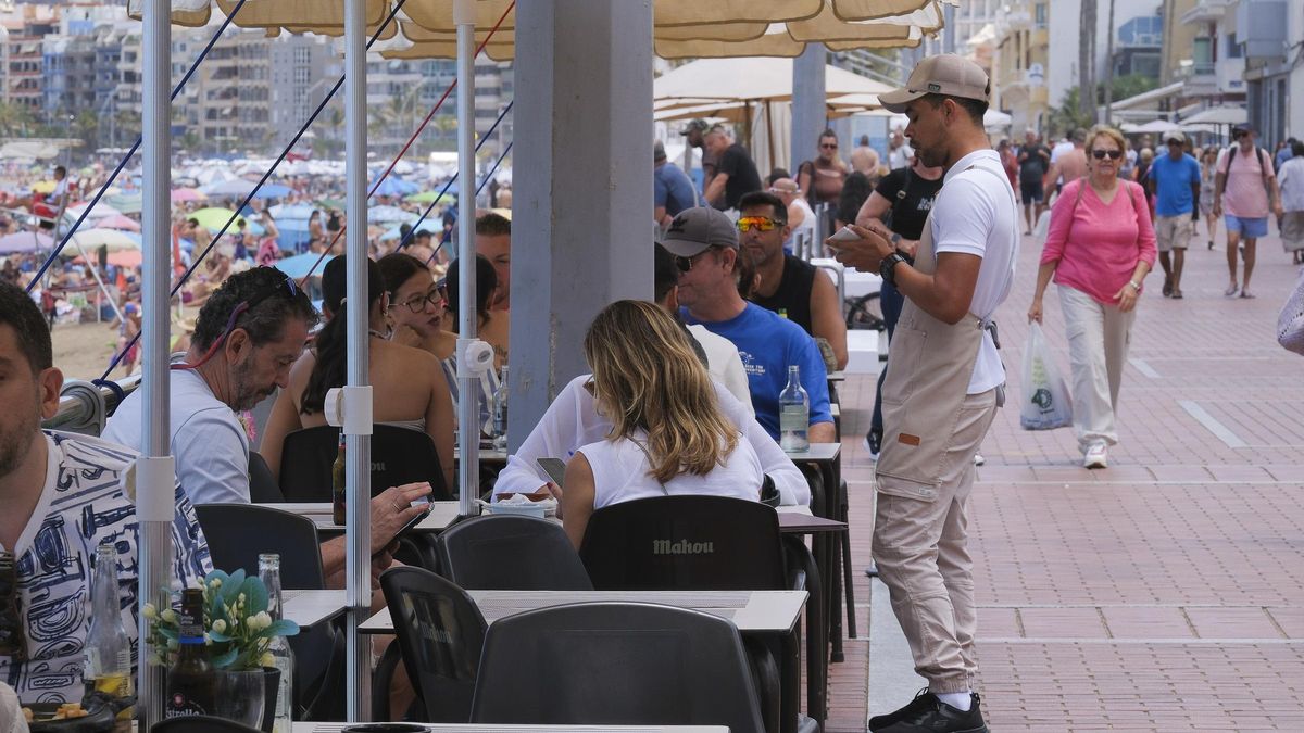 Un camarero atiende una mesa de una terraza de una playa de Canarias.