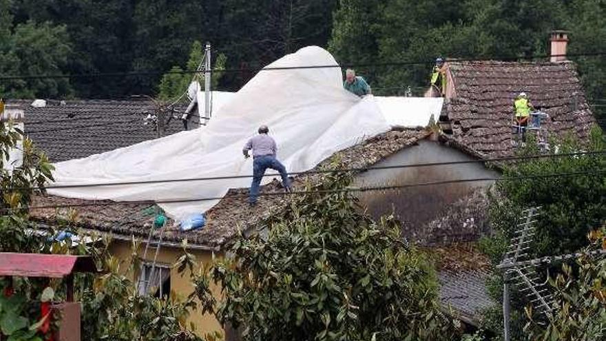 Los vecinos cubren los tejados con plásticos por la lluvia. // FdV