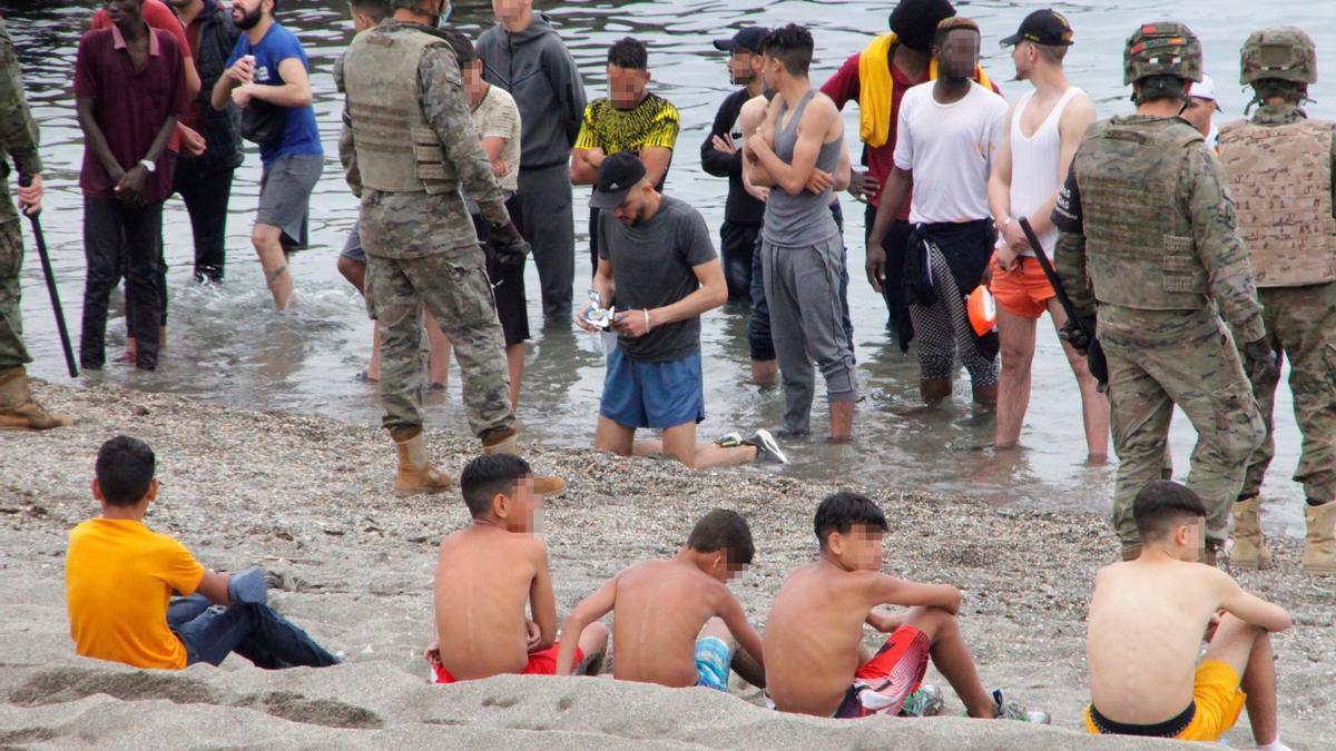 Miembros del Ejército de Tierra vigilan a un grupo de inmigrantes que han logrado cruzar la frontera.