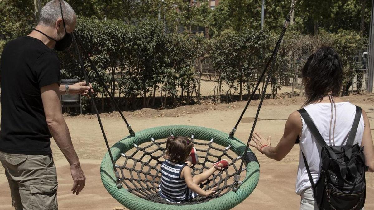 Dos padres juegan con su hija pequeña en un parque.