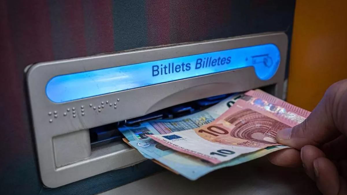Una persona retirando dinero en efectivo de un cajero.