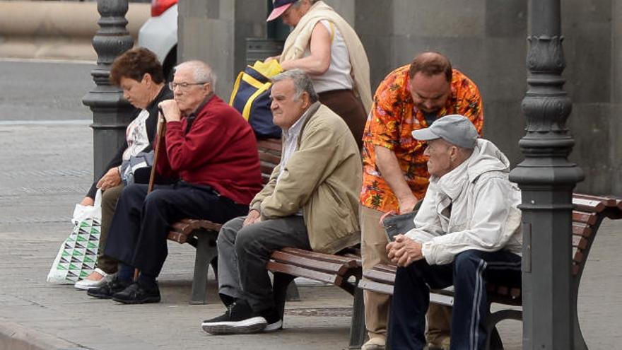 Varios jubilados descansan en los bancos de una calle de las Islas.