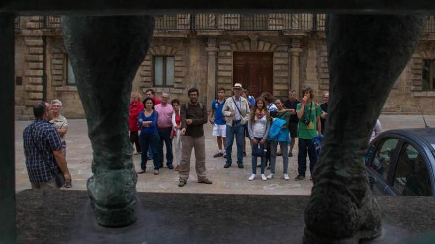 Un grupo de turistas, ante la escultura de Carreño Miranda situada en la plaza de Camposagrado.