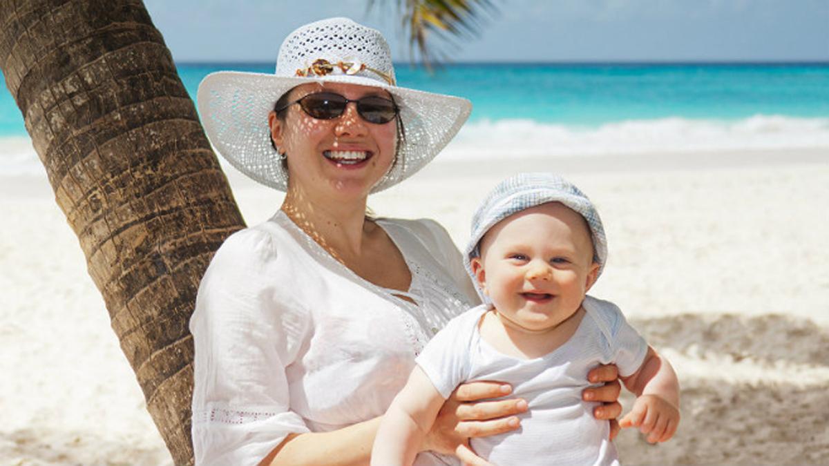 Una mujer y su bebé sonrientes en la playa