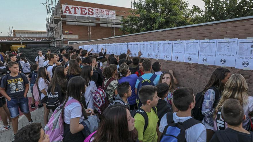 Alumnos consultando las listas publicadas en la calle antes de entrar a clase el primer día del curso en el IES de Torrellano.