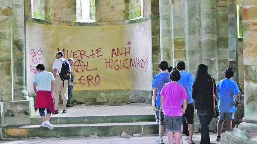 Varios vecinos de Naves, ayer, en el interior del monasterio de San Antolín de Bedón, lleno de pintadas.