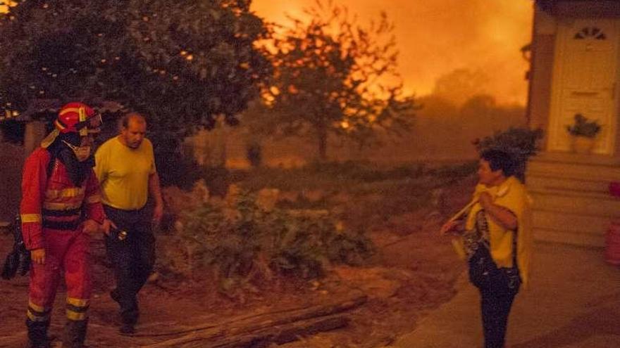 Una vecina y brigadistas a la puerta de su casa en Fraira. // B. Lorenzo