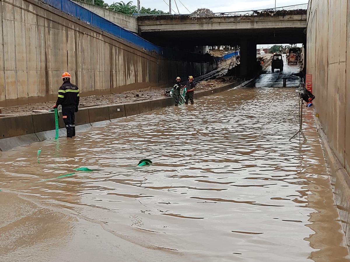 Miembros de Protección Civil sacando agua de un paso a nivel.
