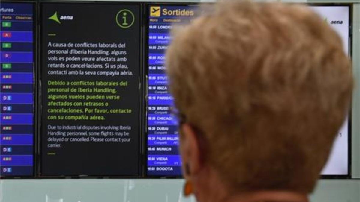 Una pasajera, ante una pantalla que informa de la huelga en el aeropuerto de El Prat.