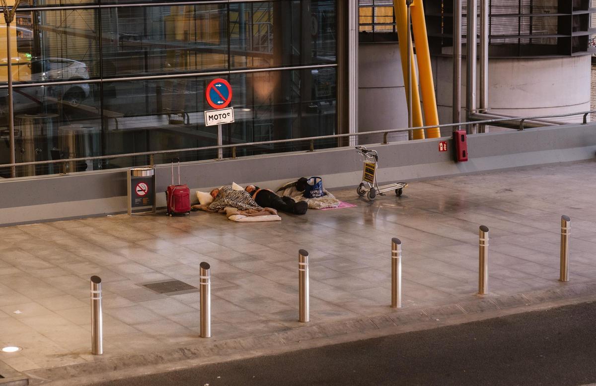 Dos personas duermen en el pasillo de la Terminal 4 del Aeropuerto Adolfo Suárez Madrid-Barajas.