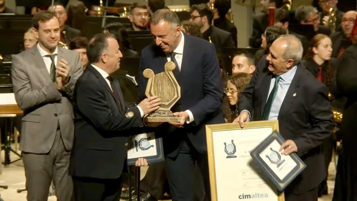 El alcalde de Altea, Dego Zaragozí entrega el Premio Villa ded Altea al director de la Banda Primittiva de Lliria ante la mirada del presidente de la banda (a la derecha)