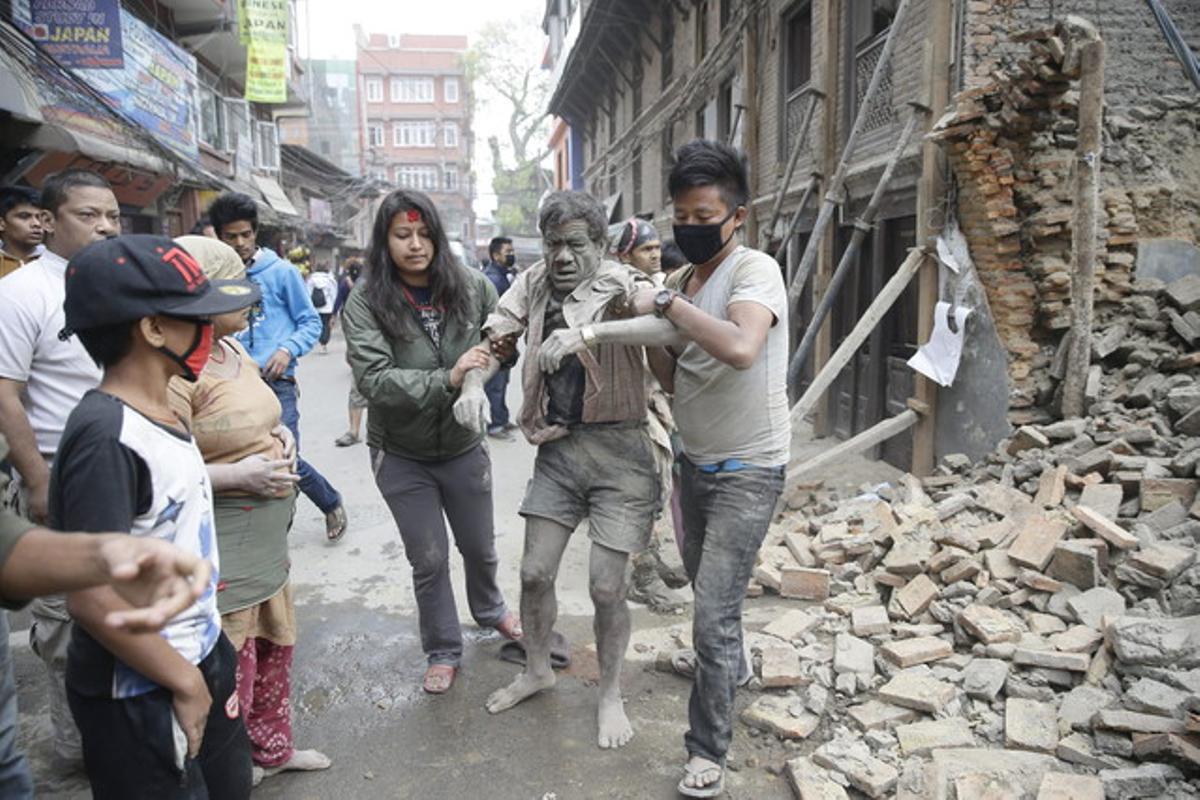 Un hombre logra ser rescatado de los escombros de un edificio de Katmandú.