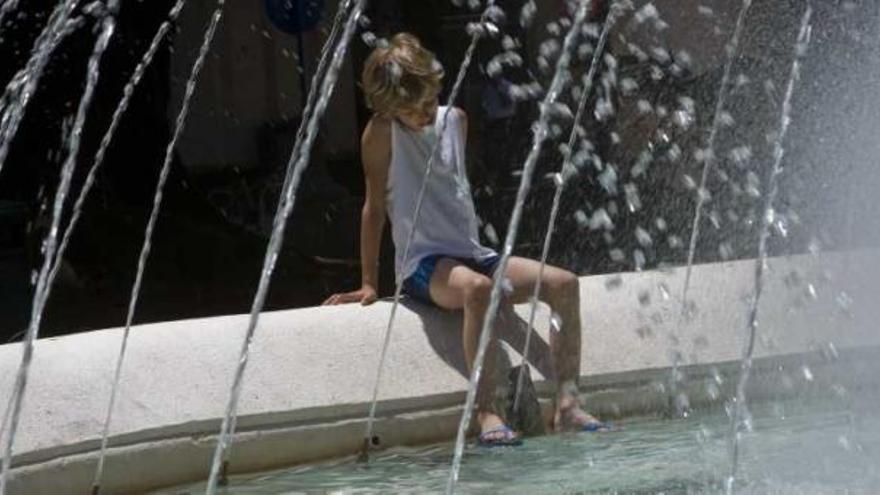 Un niño se refresca en una fuente de Alicante.