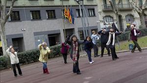 Un grupo de personas mayores practica taichí en paseo de Sant Joan de Barcelona.