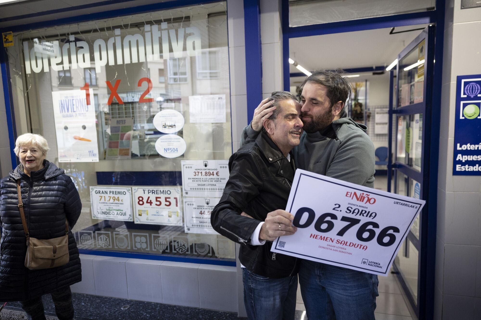 SAN SEBASTIÁN, 06/01/2025.- El responsable de la administración, Mikel Garmendia (c), celebra con su hijo Mikel (d) el segundo premio de la lotería del Niño, que ha dejado este lunes 750.000 euros correspondientes a una serie del segundo premio vendida en esta aministración del barrio de Gros de San Sebastián. EFE/Javier Etxezarreta