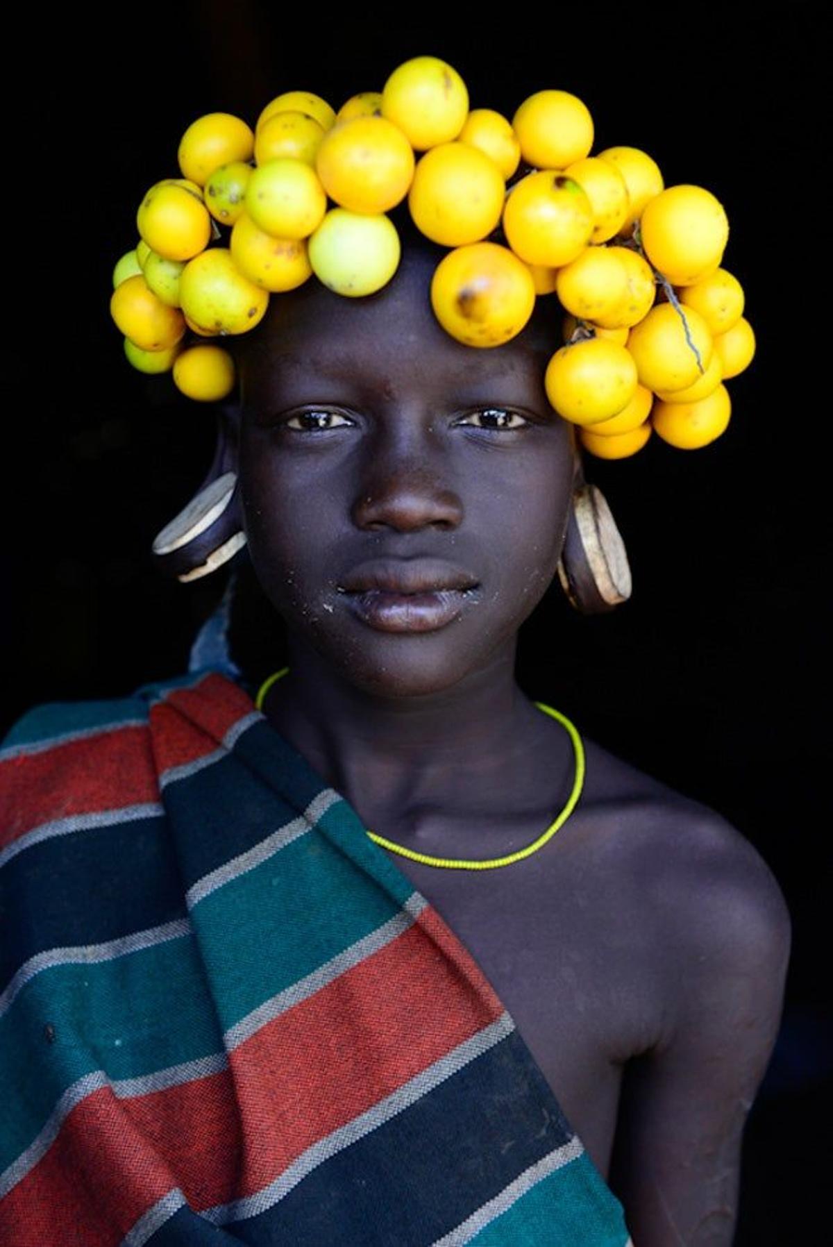 Chica mursi con frutos como decoración en el pelo