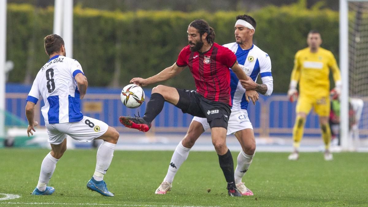 Mariano Sanz hace valer su envergadura para proteger el balón entre Diego Jiménez y Borja Díaz.