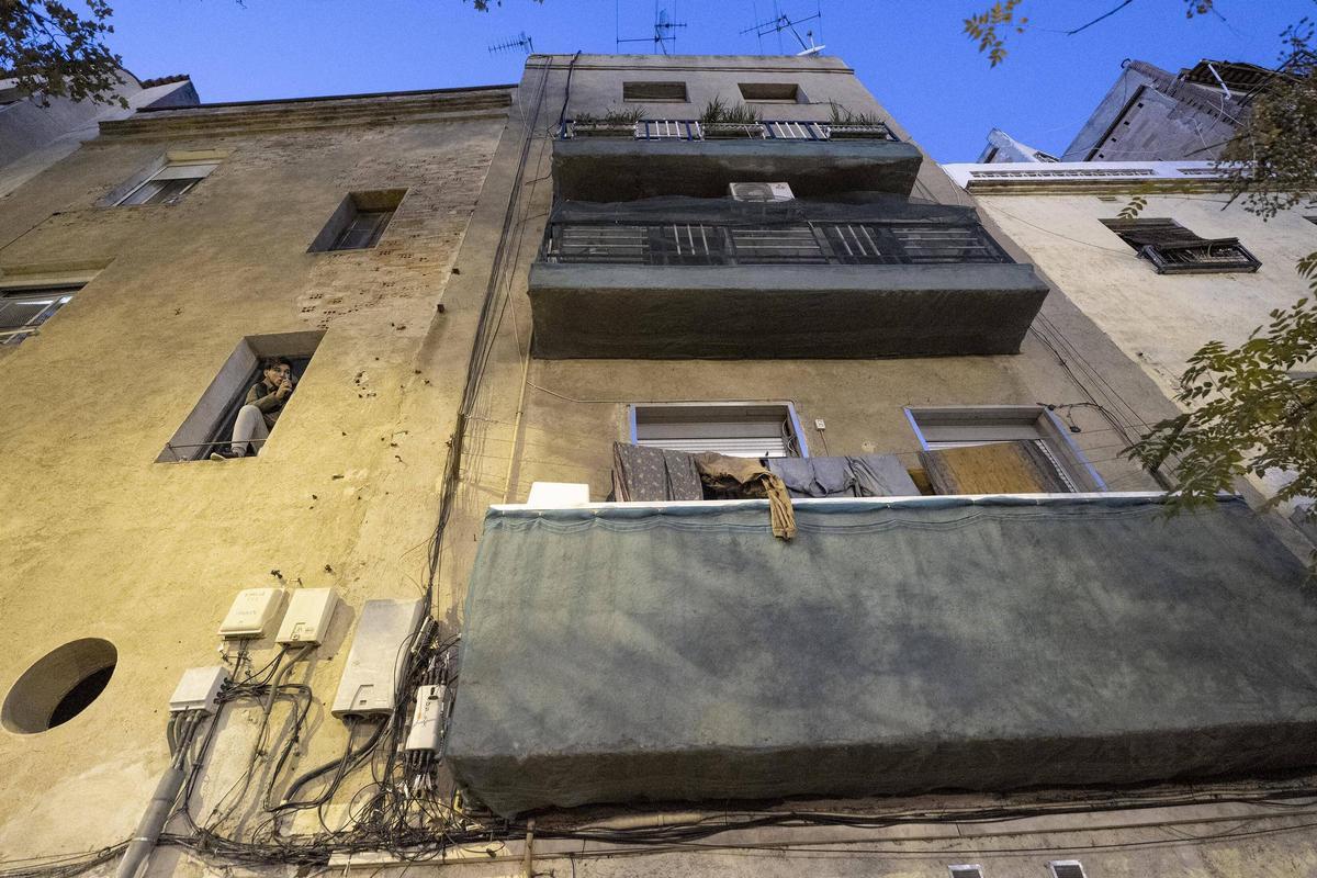 Un edificio de la Trinitat Vella con los balcones envueltos con redes para evitar la caída de cascotes, en Barcelona.