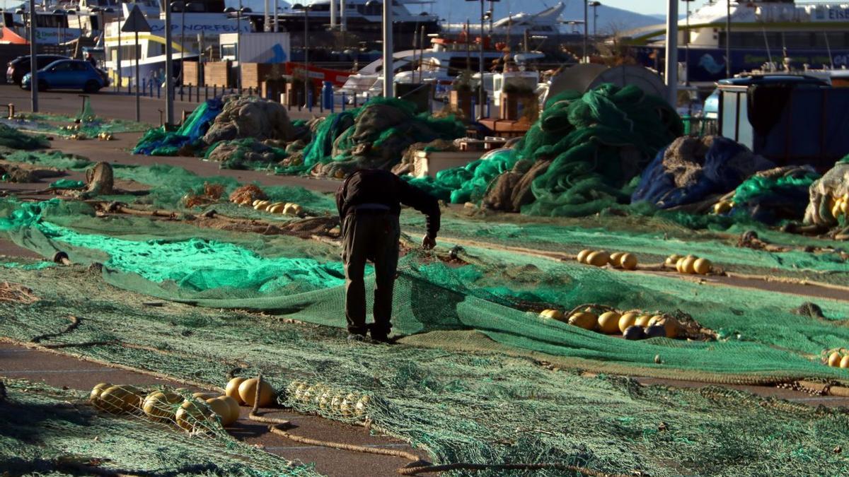 Un pescador desenredant les xarxes al port de Roses.