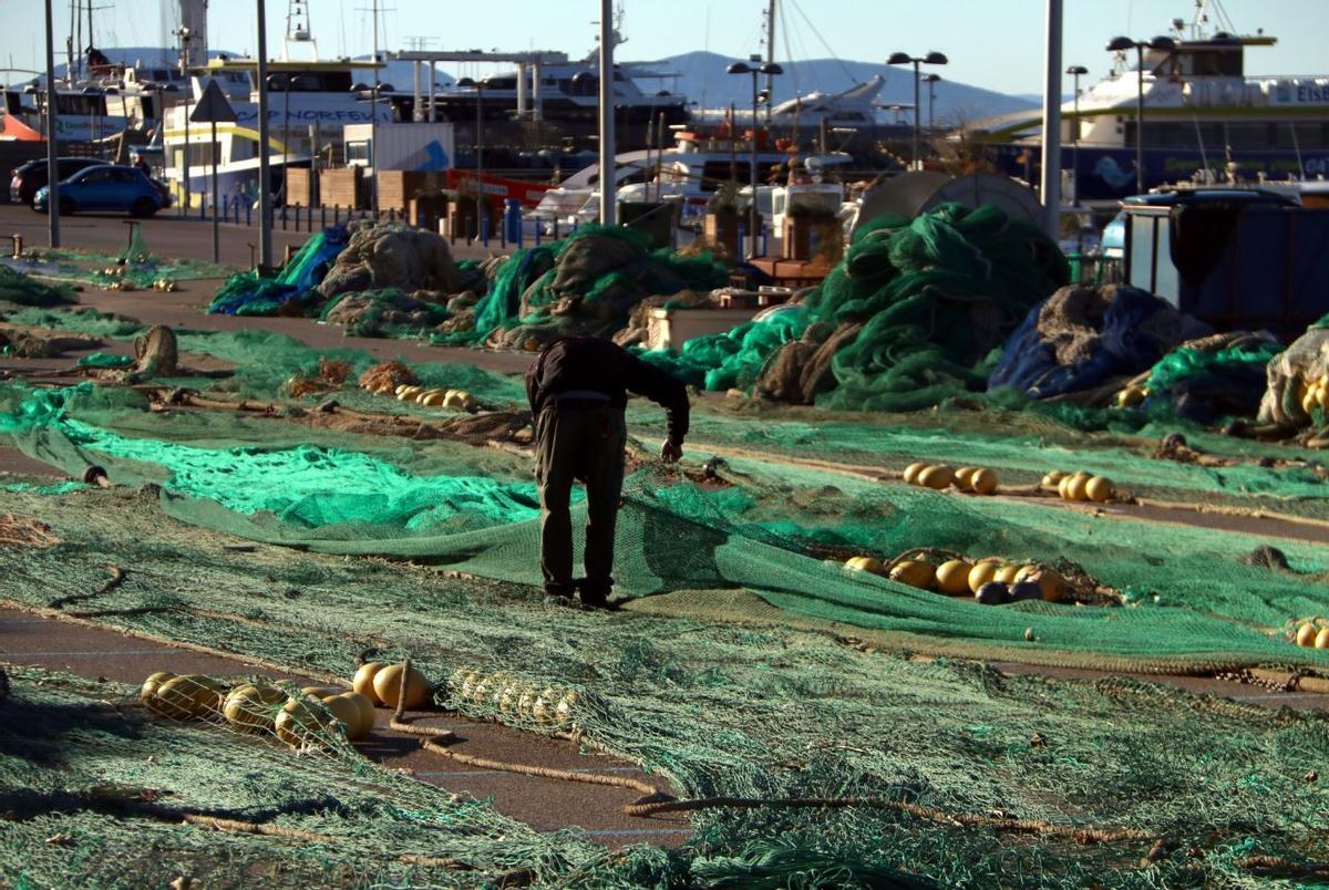 Un pescador desenredant les xarxes al port de Roses.