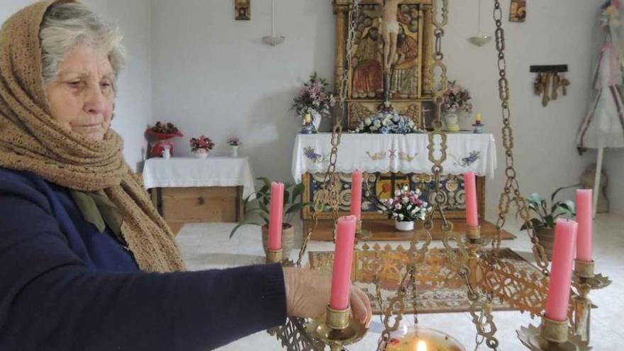 Avelina Ganado encendiendo, ayer, la lámpara de aceite en la ermita del Bendito Cristo .