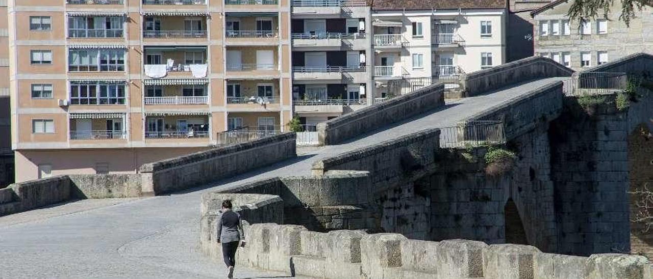 Una mujer camina por el Puente Romano a primera hora de la mañana. // Carlos Peteiro