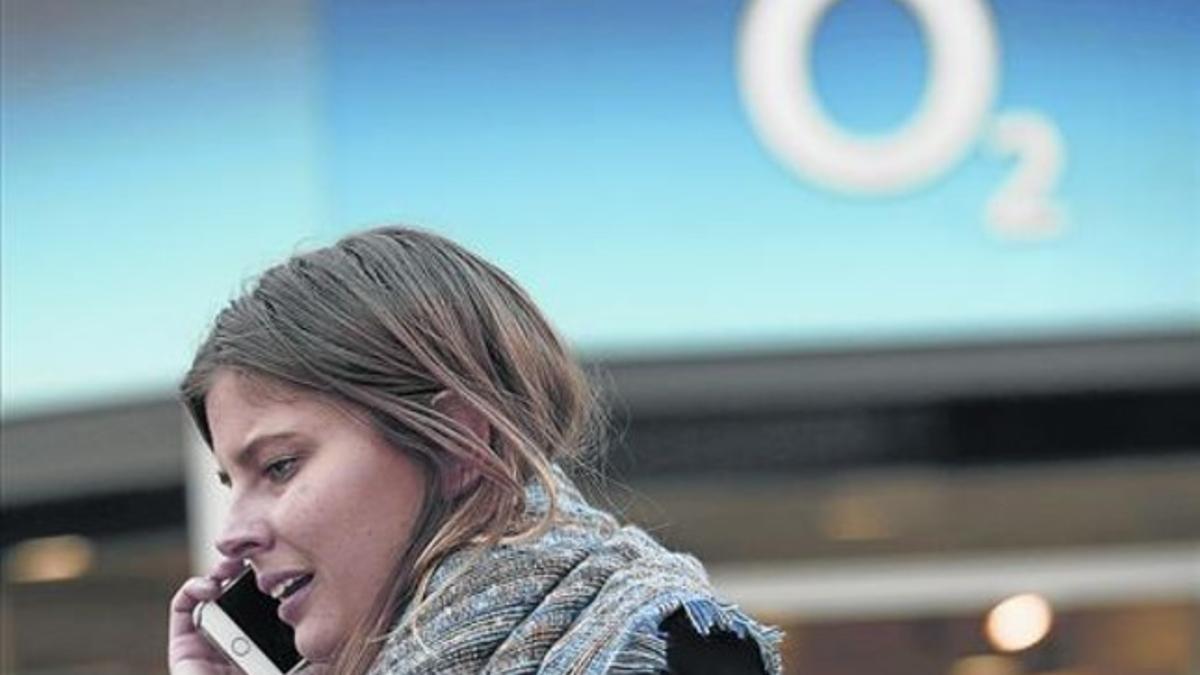 Una mujer habla por su teléfono móvil frente a una tienda de O2, ayer, en Londres.