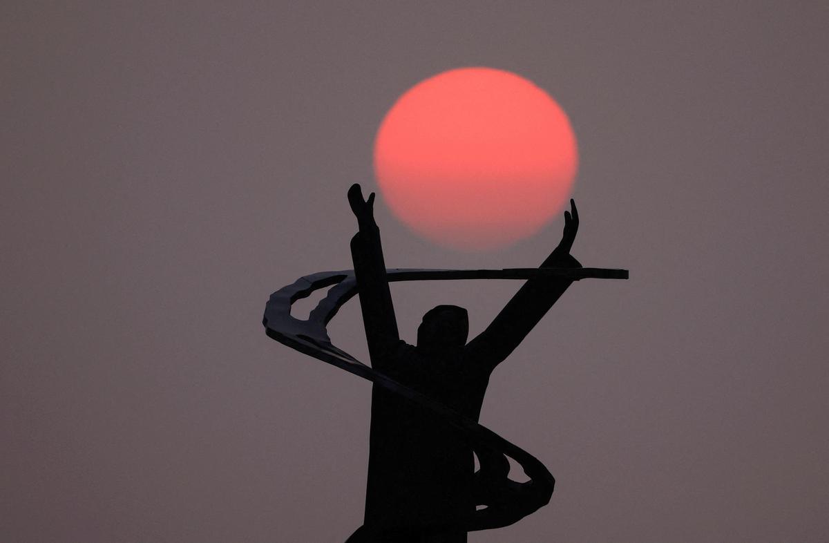 El sol se pone sobre la estatua conmemorativa de Lost at Sea en el puerto de Port-en-Bessin-Huppain, Normandía.