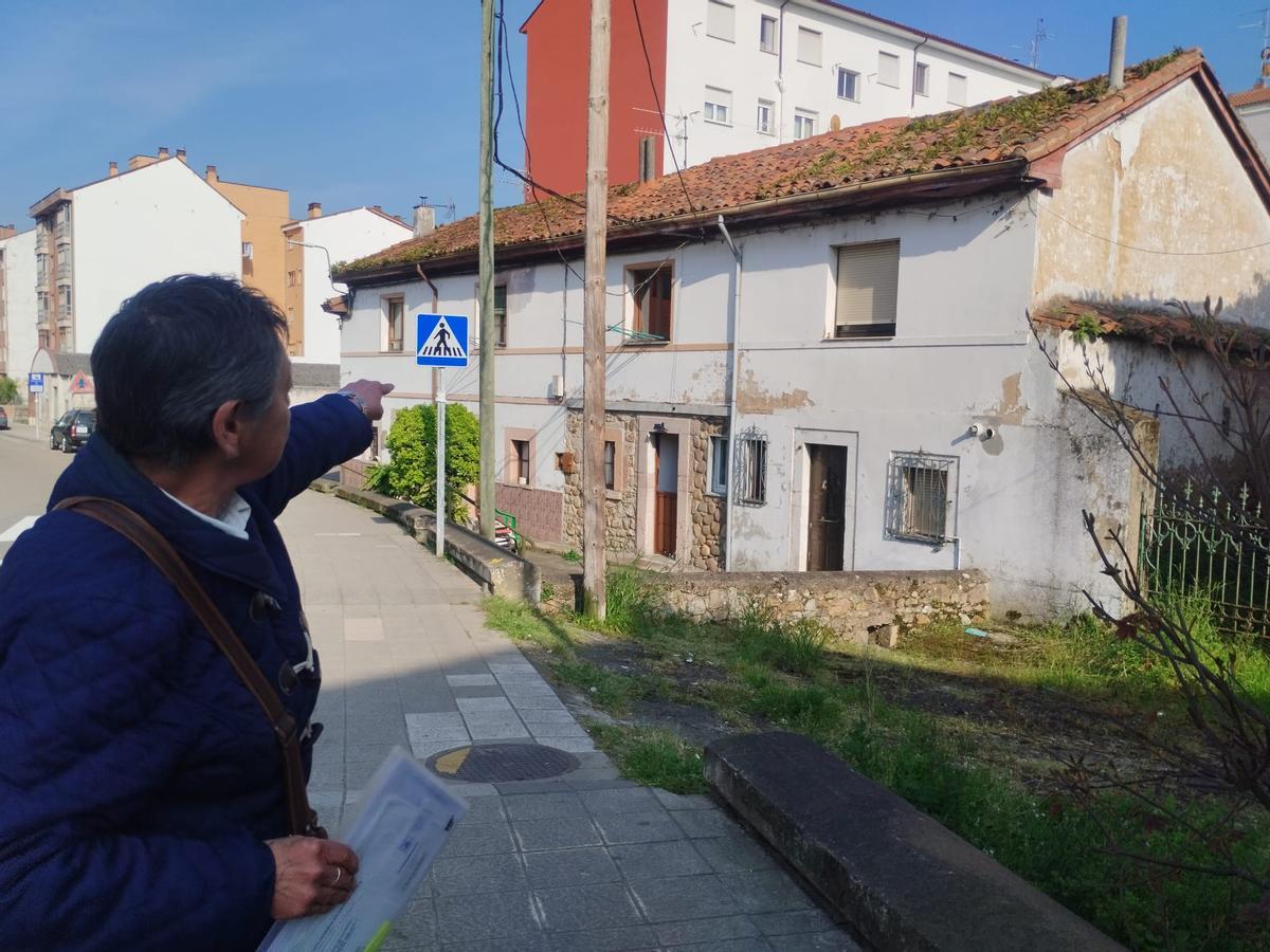 Lucía Rodríguez señala las casas adosadas dañadas por la propiedad en ruina, que es el edificio de la derecha, junto a la verja.