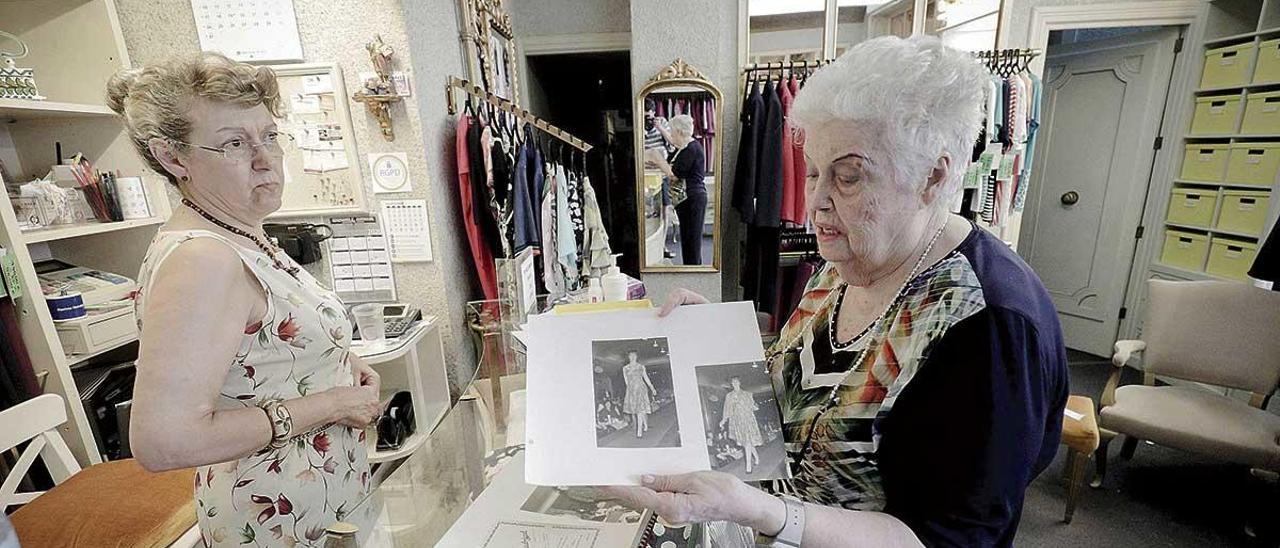 Leonor Martorell Mascaró mira a su madre, Antonia Mascaró Madrigal, mientras muestra dos fotografías de los desfiles de moda que celebraban en la tienda hace décadas.