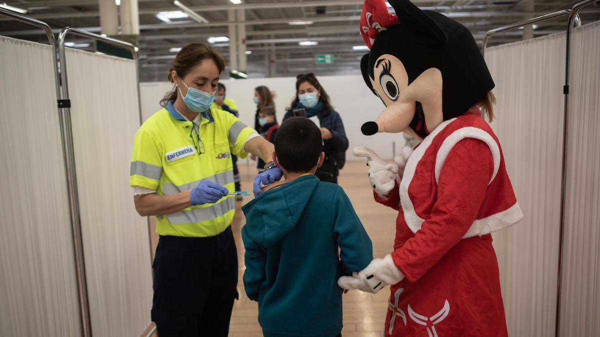 Un niño recibe la vacuna acompañado por Minnie en el Centro Comercial La Rambla, en Cartagena.