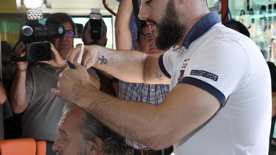 Uno de los profesionales del sector de la peluquería atendiendo a un usuario del Pelobús del Padre Ángel.