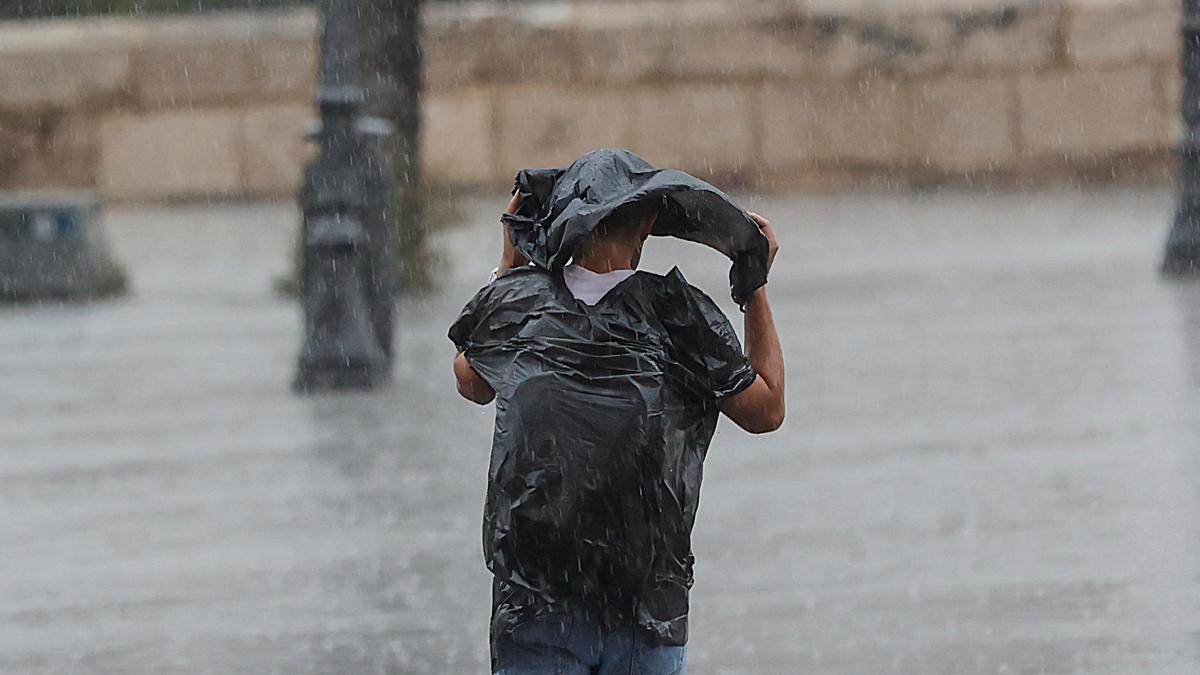 Una persona camina bajo una tromba de agua en València.