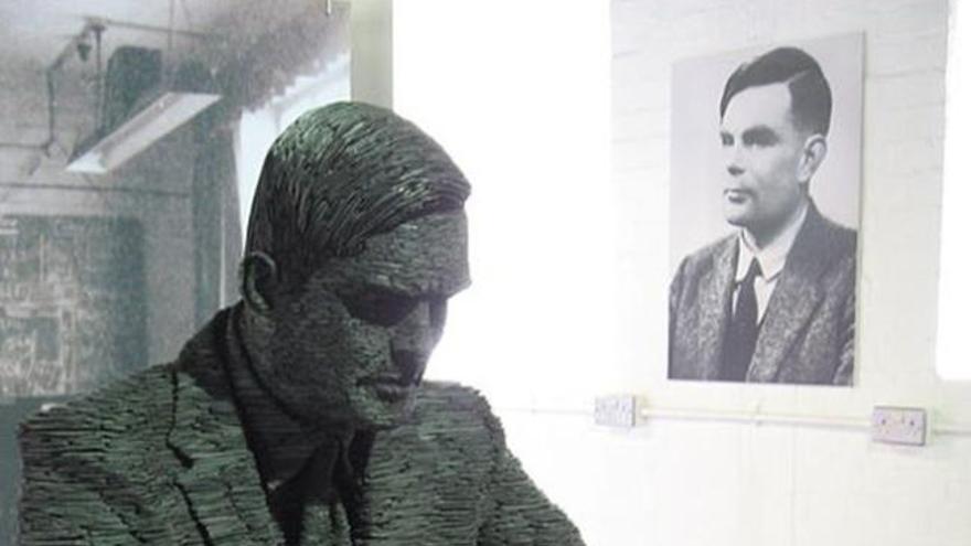 Estatua de Alan Turing con su retrato al fondo.