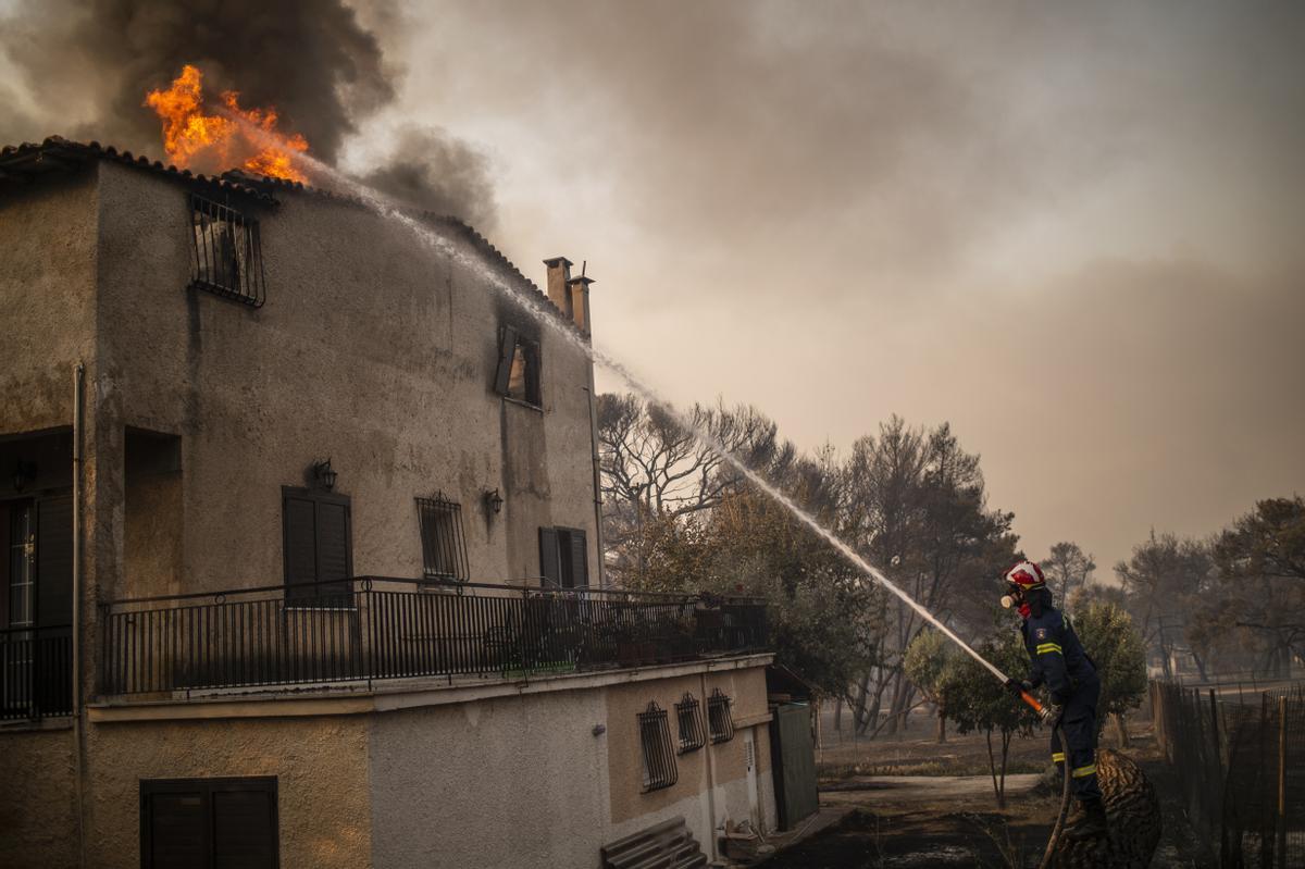 Los bomberos trabajan para apagar las llamas en una casa en el bosque, en el área de Varibobi, al noreste de Atenas.