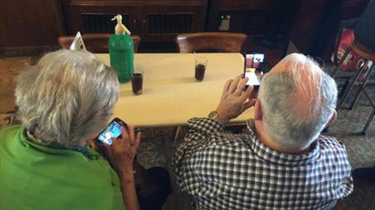Jubilados consultan sus móviles en un bar.