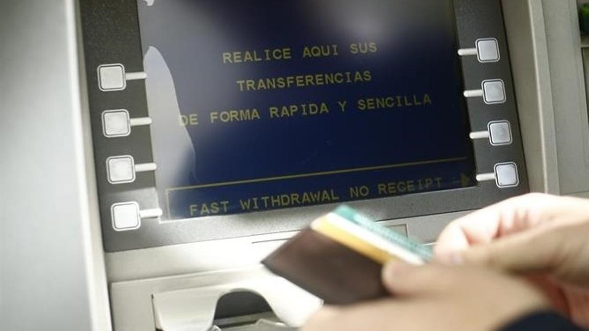 Una persona se dispone a extraer dinero de un cajero automático con una tarjeta bancara.