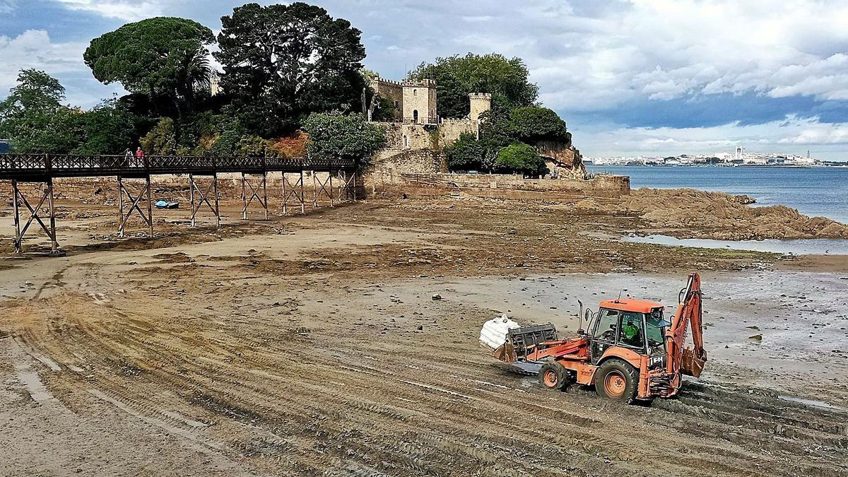 Excavadora con material de obra atravesando ayer el arenal de Santa Cruz, en marea baja, hasta el castillo.  |  // I.R.