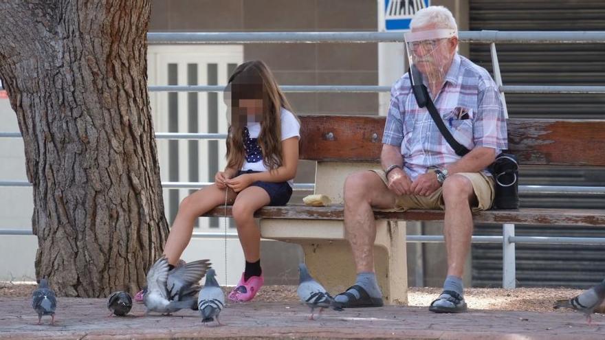 Una niña aburrida en un parque de Elda junto a su abuelo