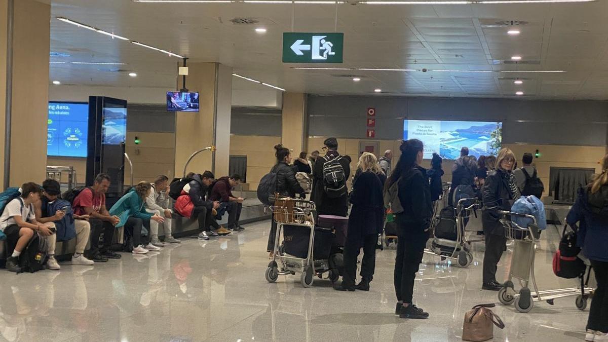 Algunos pasajeros esperan su equipaje en las cintas transportadoras del aeropuerto de Ibiza